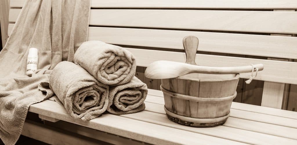 Innenraum einer Sauna mit Holvertäfelung, Kelle, Handtüchern und Eimer