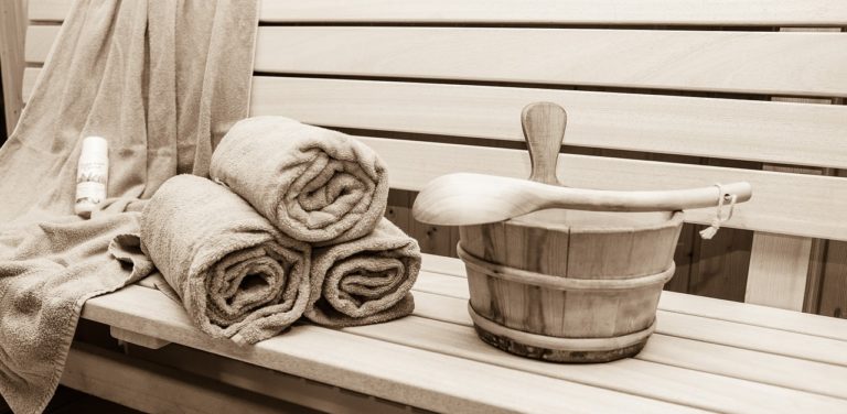 Innenraum einer Sauna mit Holvertäfelung, Kelle, Handtüchern und Eimer