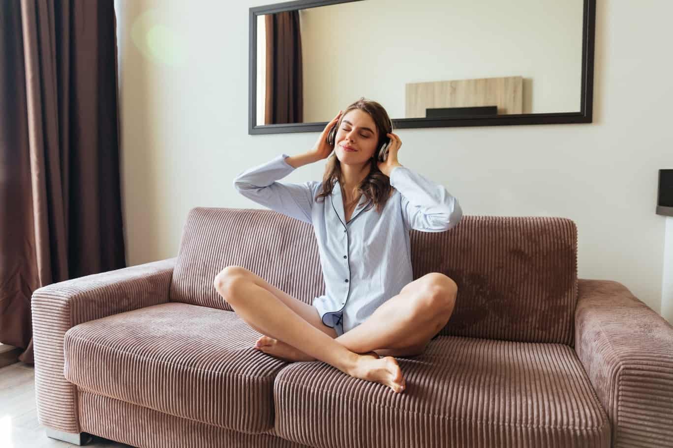 Sauna-Lautsprecher - Frau sitzt mit Kopfhörern und im Pyjama auf dem Sofa