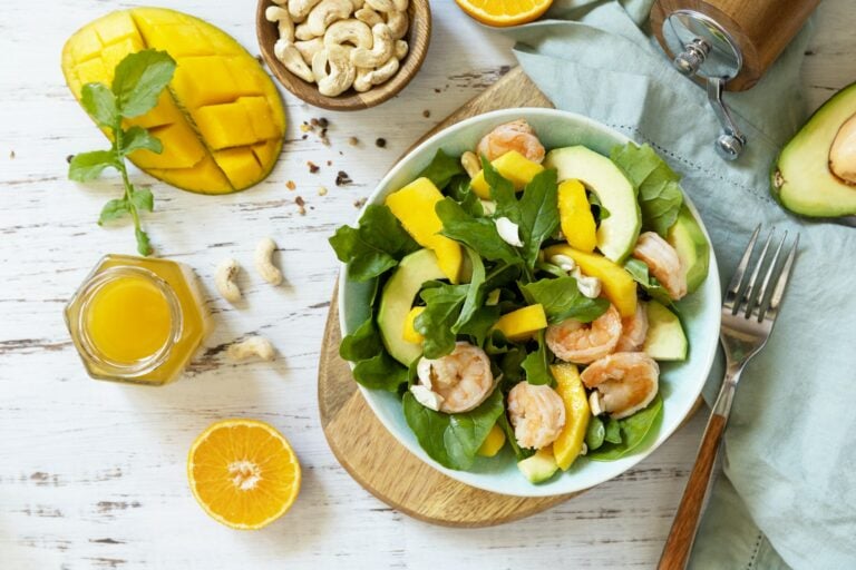 Vegetarian vegan healthy food. Salad with arugula, mango, avocado, shrimp, pecans.