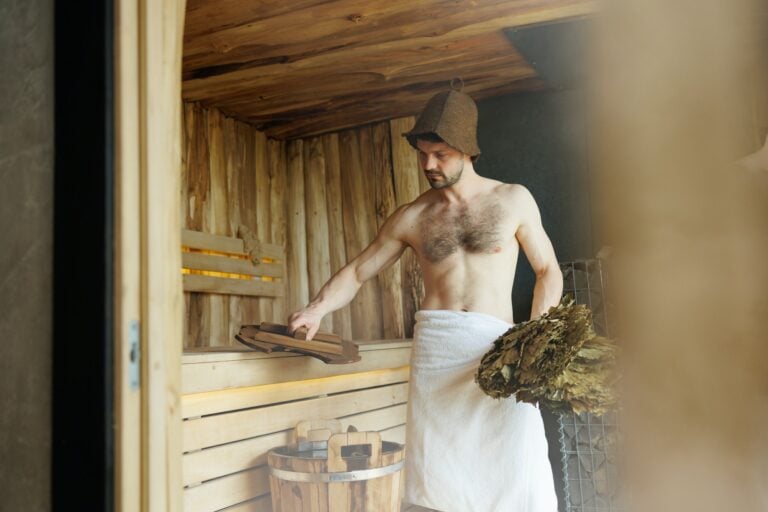 Mann mit Saunahut bereitet einen Aufguss in der Massivholzsauna vor - Titelbild Massivholz- oder Elementsauna